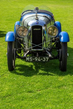 Yeşil çimen tarlasına park edilmiş mavi ve gümüş renkli bir amilcar antika bir araba.