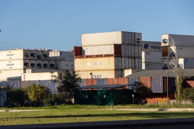 Küresel ticaret ve lojistiği temsil eden konteynır yığınları bir depoda duruyor.