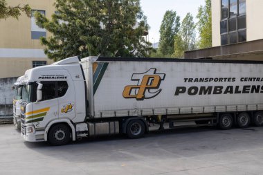Merkezi Pombalense logosuna sahip beyaz tarama kamyonu bir depo ya da otoparka park edilmiş.