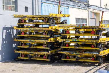 Yellow luggage dollies or baggage carts stacked and waiting outside an airport building clipart