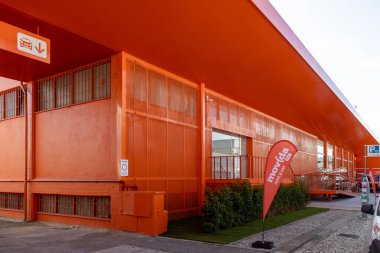 Filmin turuncu cephesi modern mimarisi ve kurumsal markası olan bir araba binası kiralıyor.