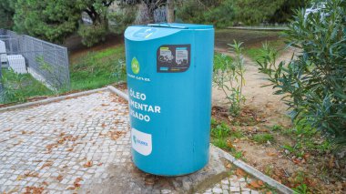 Blue recycling bin for used cooking oil in a public park promoting environmental awareness and responsible disposal practices clipart