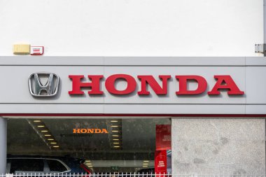 Red honda logo prominently displayed on the exterior of a car dealership building, signifying the brand's presence clipart