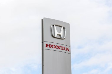 Bulutlu bir gökyüzünün arka planında ikonik logoyu gösteren Honda bayilik tabelası