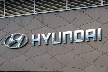 Chrome hyundai logosu, gökyüzünü yansıtan bir galeri binasının desenli duvarına monte edilmiş.