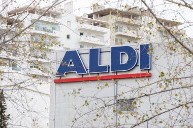 Ön planda ağaç dalları olan dış yapı üzerine Aldi süpermarket işareti