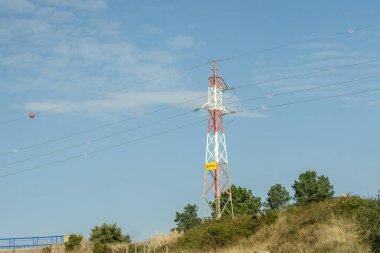 Elektrik kablolarına sabun köpüğü ve basketbol topu takılı kırmızı ve beyaz elektrik direği