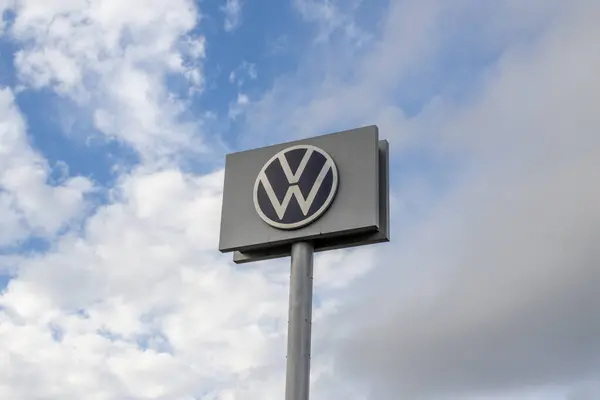 Volkswagen logosu bulutlu bir gökyüzünün arka planına karşı büyük bir tabela üzerinde belirgin bir şekilde gösterilir