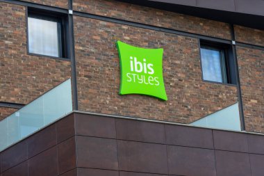 Çağdaş tuğla bina cephesine yerleştirilmiş yeşil Ibis stilli otel logosu