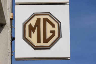 Klasik MG logosu, açık mavi gökyüzüne karşı İngiliz otomotiv markasını temsil eden bir binada belirgin bir şekilde sergileniyor.