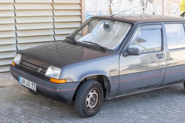 Eski, park edilmiş Renault 5 gtl ön camında güneş ışığı yansıtan bir güneş kremi