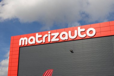 Matrizauto logosu bir binanın ön cephesinde belirgin bir şekilde sergileniyor, bulutlar ve mavi gökyüzüne karşı kuruluyor.