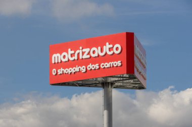 Kırmızı matrizauto reklam panosu bulutlu gökyüzüne karşı dik duruyor Portekiz 'de araba alışverişi yapıyor.