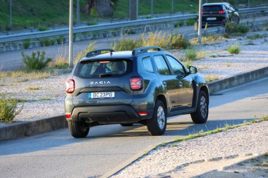 Dacia duster driving on asphalt road during the day clipart