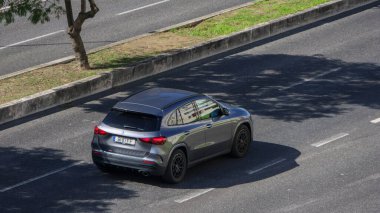 Modern gri Mercedes Gla, şehir ortamında asfalt bir yolda sürerken, çağdaş ulaşıma bir bakış sunuyor.