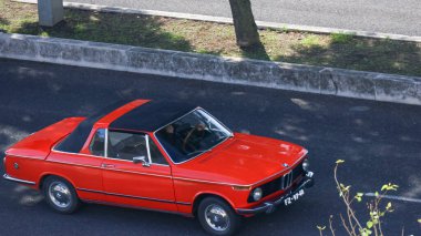 Klasik kırmızı bmw 2002tii asfalt yolda sürüyor