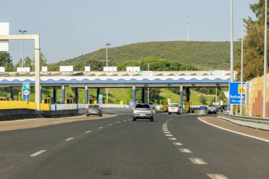 Güneşli bir günde Portekiz 'de otoyolda gişeye yaklaşan arabalar var.