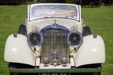 Klasik beyaz Bentley otomobil çimenli bir alana park edilmiş, klasik zarafetini ve zamansız tasarımını sergiliyor.