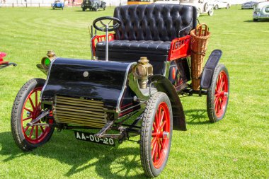 Klasik bir araba fuarında çimlere park edilmiş deri koltukları ve hasır sepeti olan eski model bir araba.
