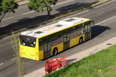 Lizbon, Portekiz 'de çok şeritli bir yolda giden sarı şehir otobüsü.