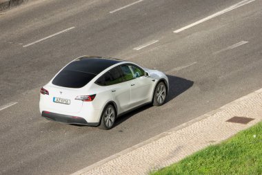 Beyaz Tesla modeli çok şeritli bir otoyolda gidiyor.