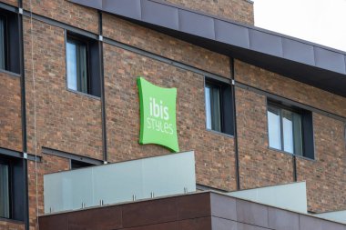 Yeşil Ibis tarzı logo modern bir otelin tuğla duvarına iliştirilmiş.