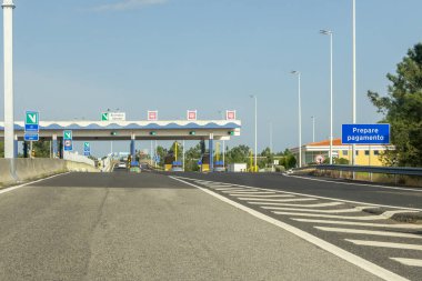 Otobandaki boş gişelerde mavi gökyüzünün altında yaklaşan araçlar var.