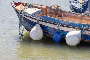 Boya, çamurluk ve iplerle dolu yıpranmış bir balıkçı teknesi, sakin sularda yüzüyordu.