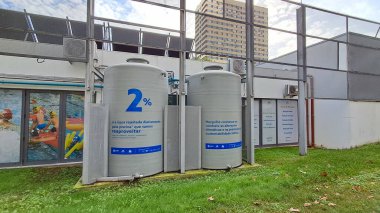 İki büyük su tankı halka açık bir havuzun dışında duruyor, suyun yeniden kullanımını teşvik ediyor ve tesisin sürdürülebilirliğe olan bağlılığını vurguluyor