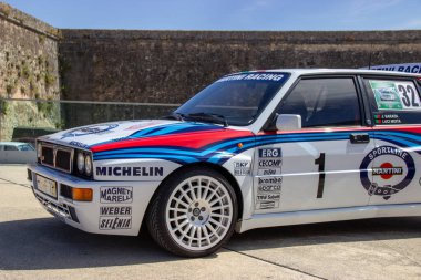 Efsanevi Lancia delta integrali. Evrimleşen martini. Taştan bir duvarın yanında park edilmiş.