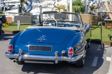 Klasik mavi Mercedes Benz 190 sl vintage araba lüks bir marinada park edilmiş, sofistike ve otomotiv tarihinin simgesi.
