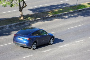 Mavi Tesla modeli. Yazın asfalt yolda elektrikli araba.