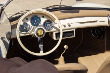 Klasik bir Porsche 'nin iç görünümü, bej gösterge paneli, direksiyon simidi, göstergeler ve vites kolu.