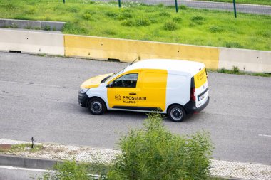 Beyaz ve sarı fukaralar, asfalt yolda giden güvenlik minibüsleri.