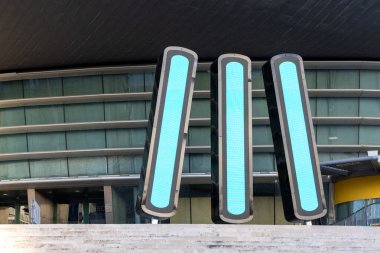 Cyan mavisi ekranlı üç yüksek ışık sütunu, Lizbon, Portekiz 'deki Altice Arena' nın modern mimarisinin önünde duruyor.