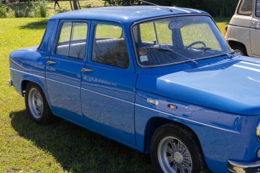 Klasik mavi renault 8 gordini çimenli bir alana park etmiş klasik cazibesini ve spor tasarımını sergiliyor.