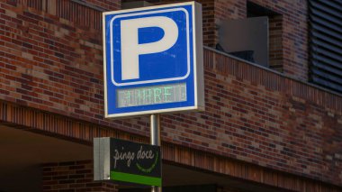 Portekiz 'deki Pingo Dodge süpermarketinde, tuğla bir duvarın önünde park alanlarını gösteren bir tabela.
