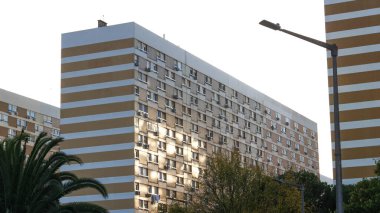 Şehir merkezindeki apartman cephesinin pencerelerine yansıyan güneş ışığı