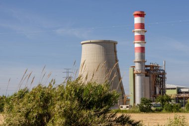 Portekiz 'de mavi gökyüzüne karşı yükselen bir termoelektrik santrali olan ribatejo güç istasyonunun soğutma kulesi ve bacası.