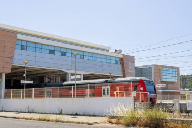 Cp comboios de Portekiz tarafından işletilen Castanheira do ribatejo tren istasyonunda açık mavi gökyüzü altında bekleyen kırmızı ve gri modern tren.