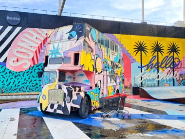 Önünde Ubbo alışveriş merkezinin merkezi meydanında park etmiş bir alışveriş arabası bulunan canlı çift katlı otobüs sanat kurulumu Lizbon, Portekiz