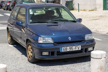 Koyu mavi renault bir klimanın önü caddeye park edilmiş, güneşli bir günde tasarımı ve durumu gözler önüne seriliyor.