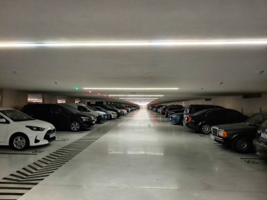 Park halindeki araçlar, modern aydınlatma donanımlarıyla aydınlatılmış bir yeraltı otoparkını işgal ediyor.