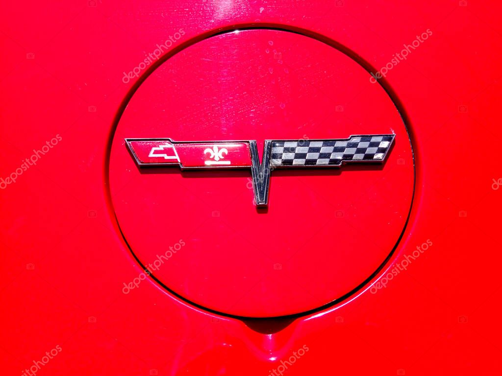 Close up of a red corvette's gas cap, showcasing the iconic racing flag and fleur de lis logo