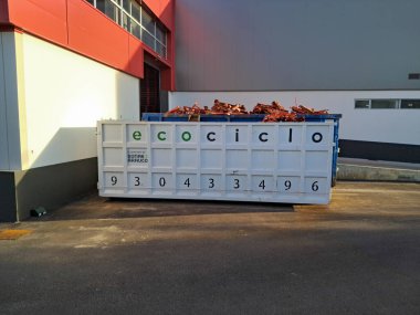 Endüstriyel çöp konteyneri geri dönüşüm için odun atıkları topluyor, inşaat veya imalatta çevre sorumluluğunu destekliyor