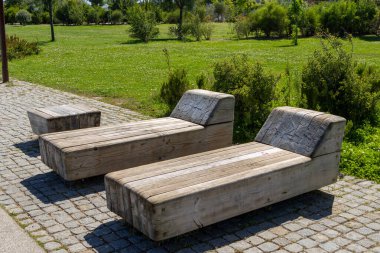 İki kırsal ahşap bank rahatlamak ve yeşil bir park manzarasının huzurlu manzarasının tadını çıkarmak için bir yer sunuyor.