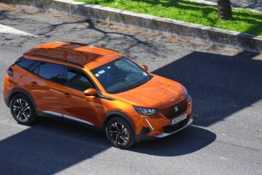Modern turuncu peugeot 2008 SUV asfalt yolda kaldırımın yanında sürüyor