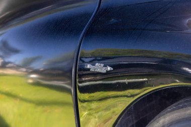 Eski model siyah bir otomobilin cilalı çamurluğuna yapıştırılmış 4 cv renault logosunu kapat