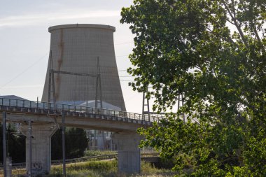 Portekiz 'de bir köprü ve ağacın arkasındaki Ribatejo termoelektrik santralinin soğutma kulesi.
