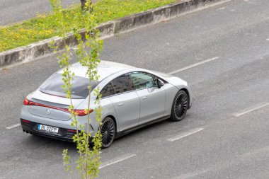 Modern gümüş Mercedes Eqs asfalt yolda gidiyor.
